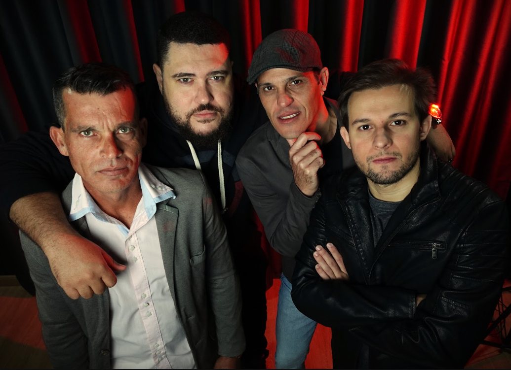 Os quatro integrantes da Banda Groove diante de uma cortina vermelha